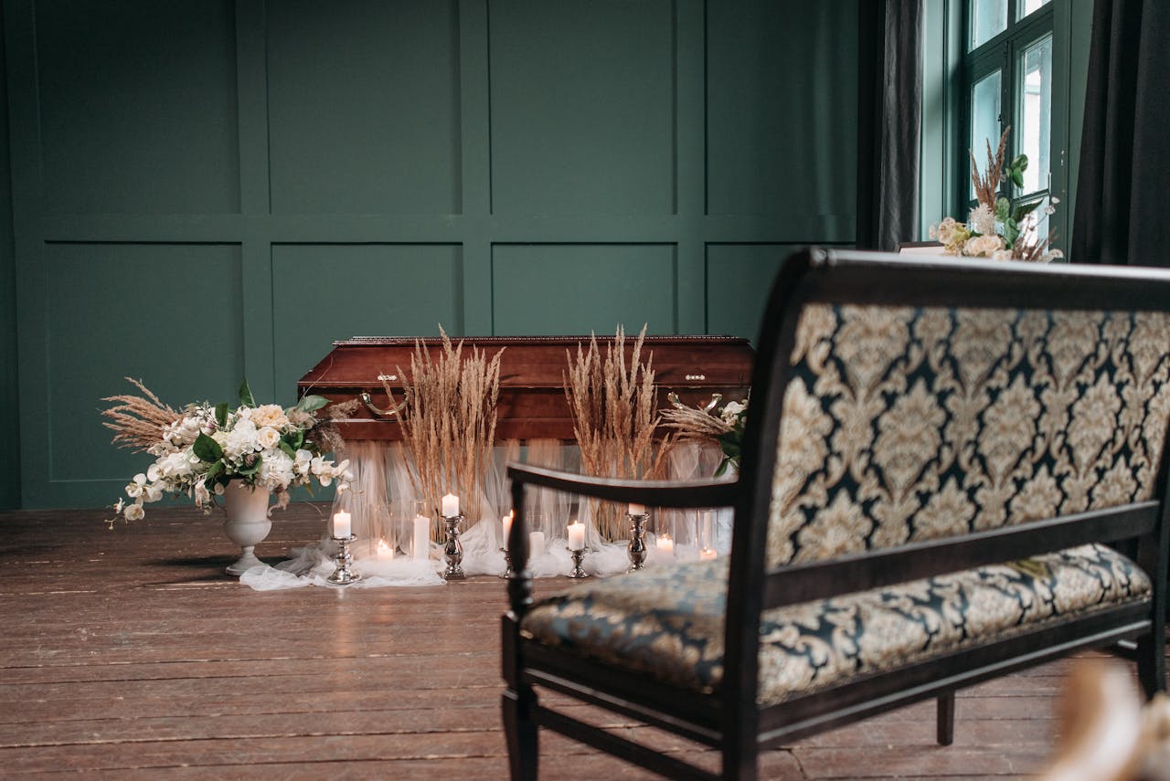 A beautifully decorated funeral room featuring a coffin, flowers, and candles set in a serene atmosphere.